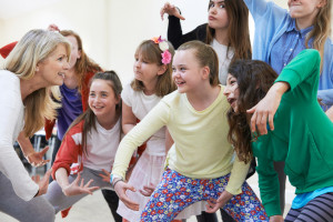 Group Of Children With Teacher Enjoying Drama Class Together